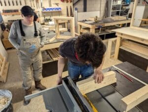 Een cursist zaagt zijn hout met de cirkelzaag machine tijdens de basis cursus timmeren.