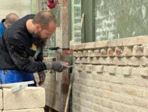 Cursist tijdens de snelcursus metselen bezig met het bouwen van een oefenmuur.