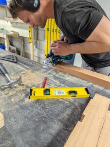Cursist zaagt hout met cirkelzaag tijden cursus houtbewerken.
