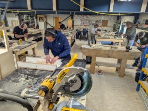 Cursisten leren houtbewerken tijdens cursus houtbouw.