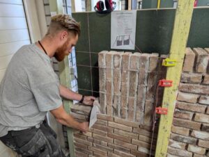 een cursist metselt een anderhalf steen rollaag tijdens de metselcursus in helmond.