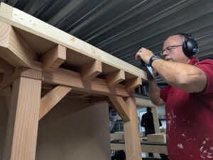 Cursist leert tijden houtbewerken een overkapping timmeren.