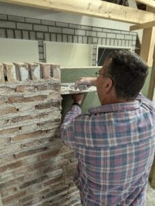 Een cursist voegt zijn gemetselde muur tijdens de basis cursus metselen.